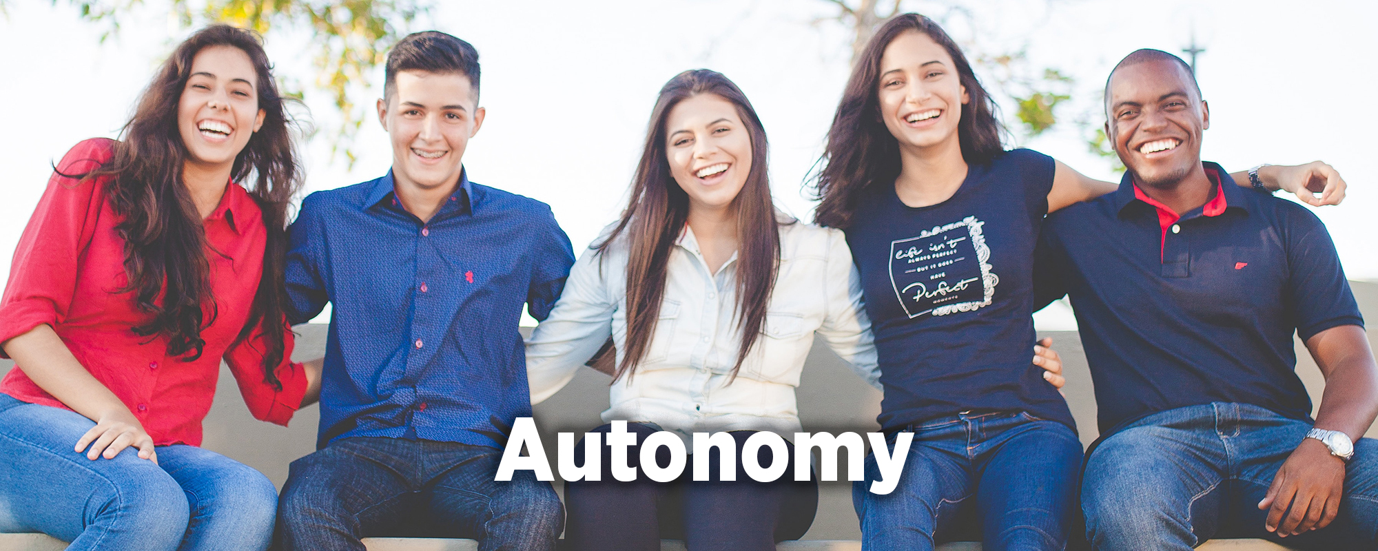 Five young adults sitting on a bench and smiling.